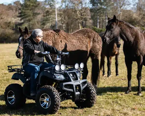 Man Riding Explorer GT Electric Quad Bike In Horse Field With Horses